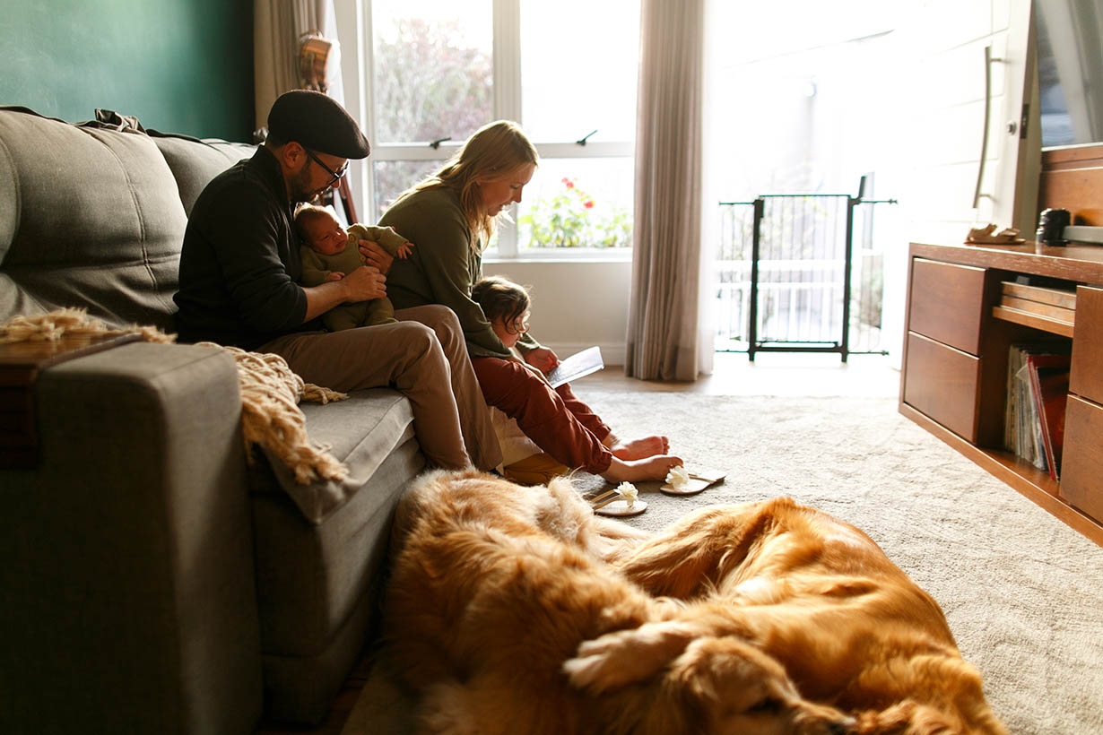 Young happy family with newborn baby sitting on the sofa