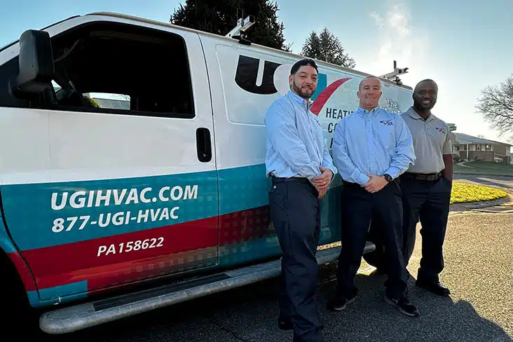 Three technicians standing next to their work van