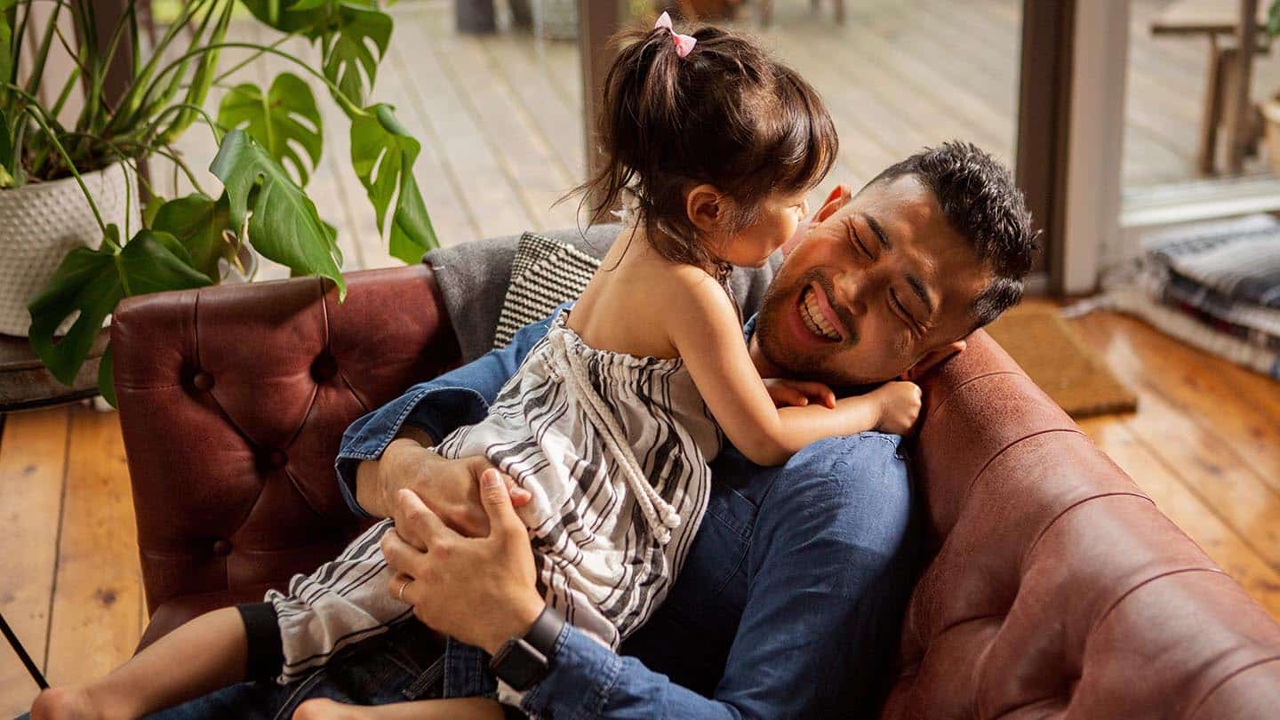 High angle view of cheerful father with daughter relaxing on sofa at home UGI may24 Hero 1440x810 1